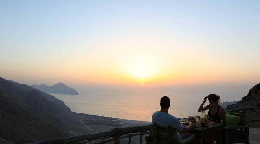 Couple eating dinner at Six Senses Zighy Bay overlooking a fantastic view on a wellness retreat