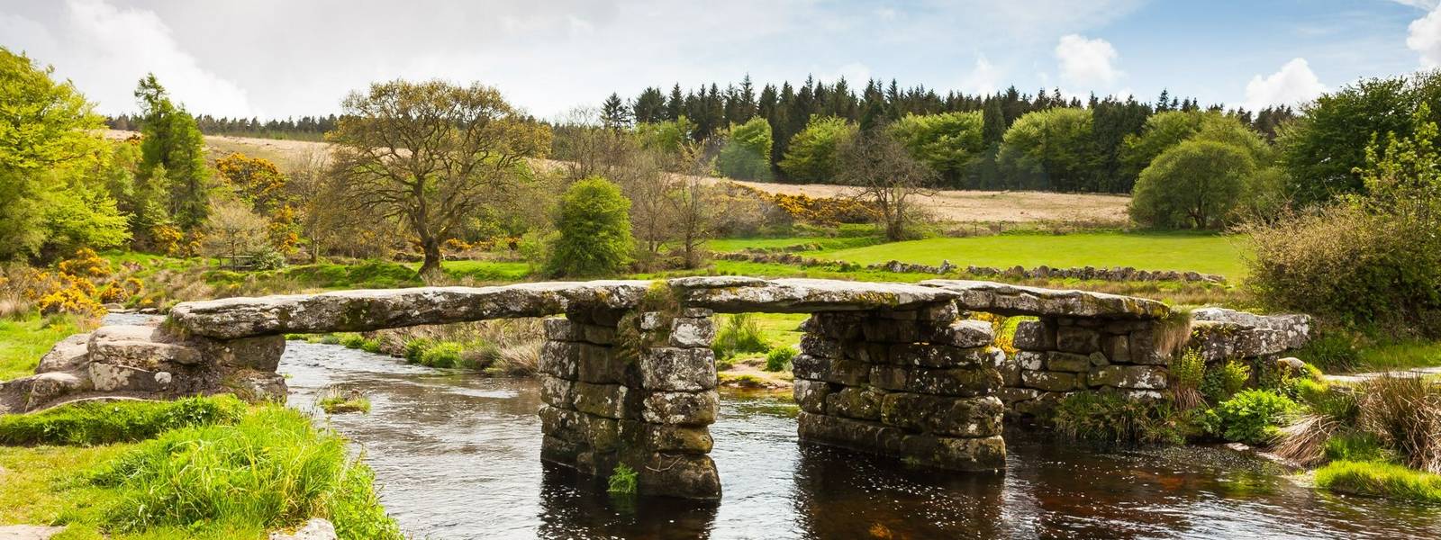 Ancient clapper bridge over the East Dart river at Postbridge in Dartmoor National Park in Devon UK Europe
