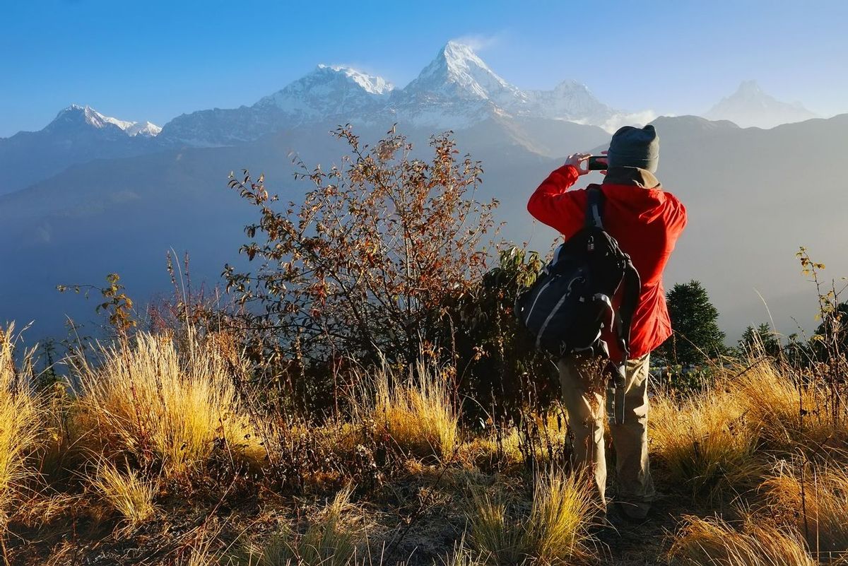 Tourist, a man, makes photo of Annapurna mountain with his mobile phone from Poon Hill, famous view point in Himalaya range …