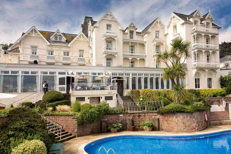 Scenic view of a hotel with a swimming pool next to a white building.