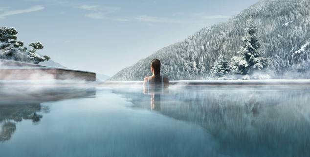 Woman in the outdoor pool at Lefay Resort and Spa Dolomiti overlooking the Dolomite mountains