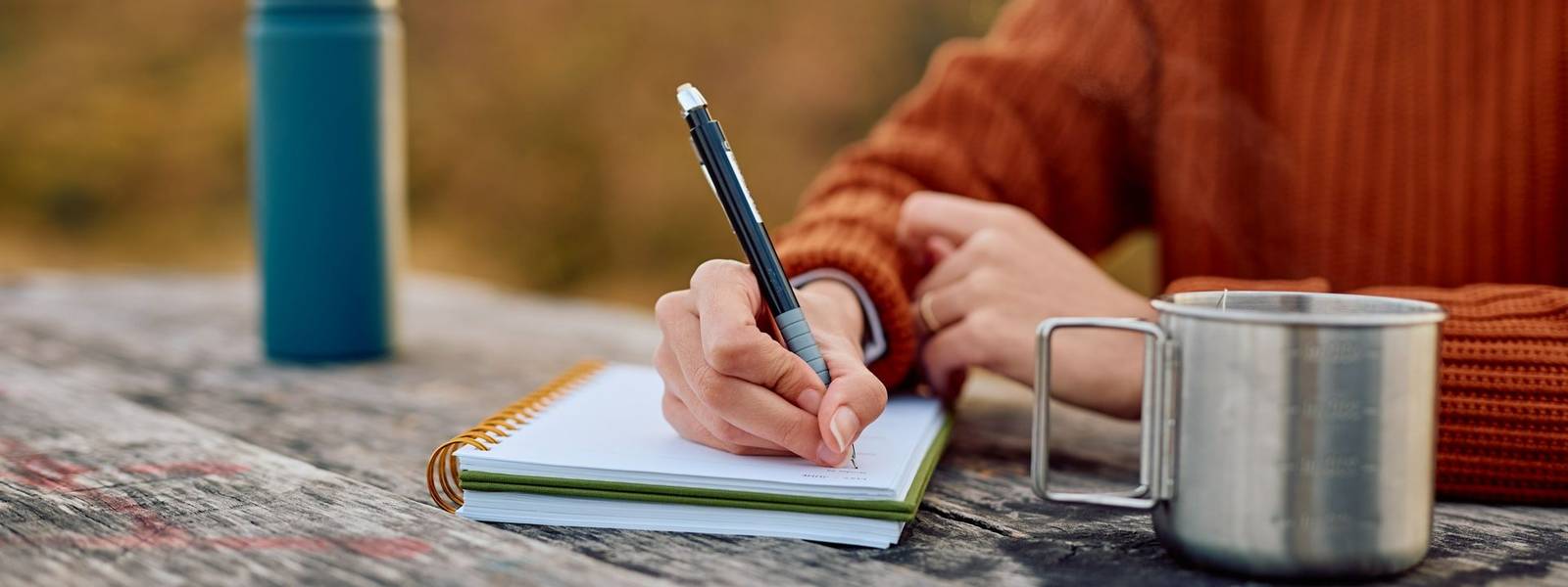 Person writing in journal outdoors during autumn travel
