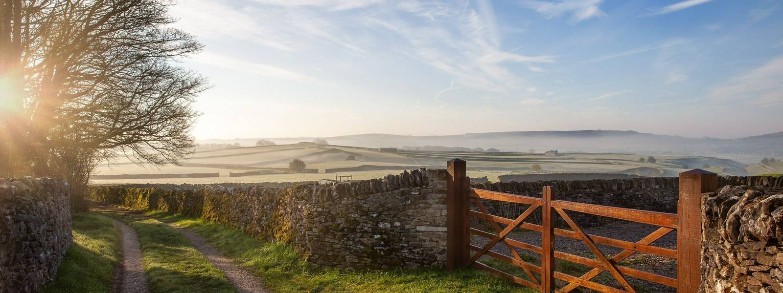 Sunrise in the Peak District. Wooden farm  gate and dry stone walls with frosty fields and blue skies