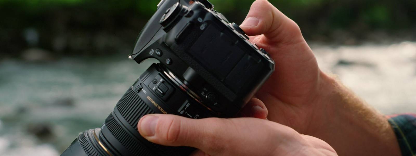 Closeup man hands holding photo camera outdoor. Male photographer using digital camera. Unrecognizable guy fingers pressing …