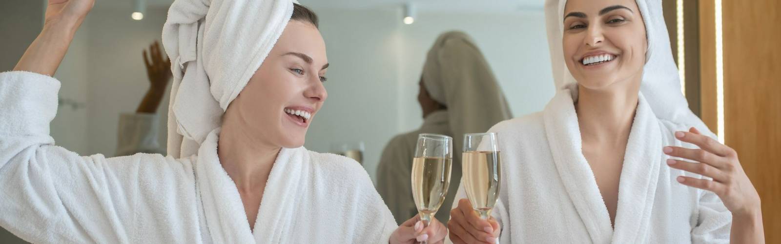 Spa weekend. Two pretty girls in white robes drinking champagne and enjoying