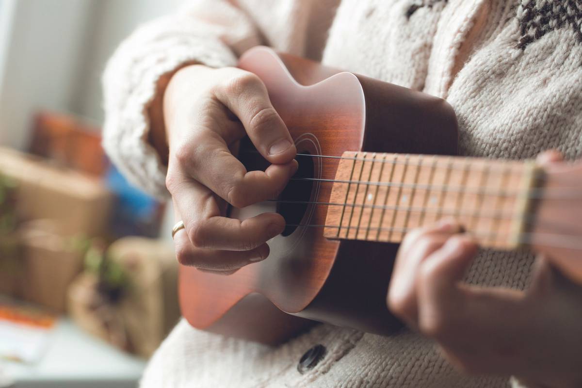 Close up of woman playing ukulele.