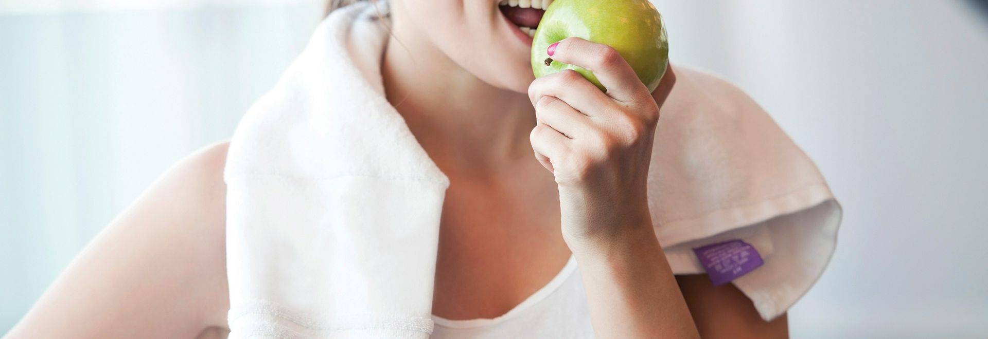 Young woman eating apple on a workout break