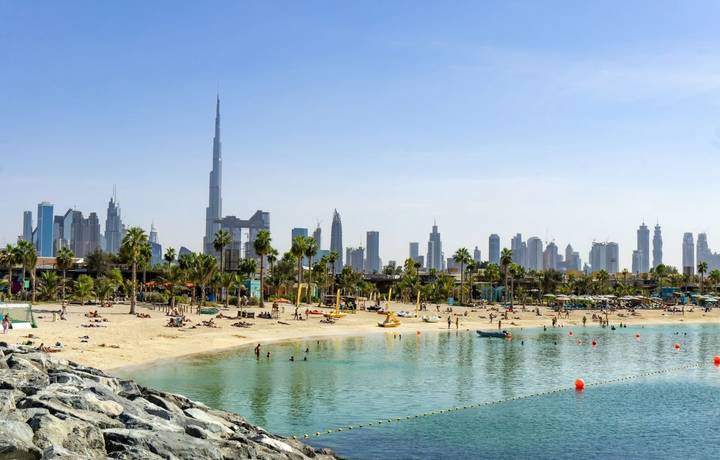 Beach in Dubai with people and skyscapers in the background on a sunny day Beach in Dubai with people and skyscapers in the background on a sunny day