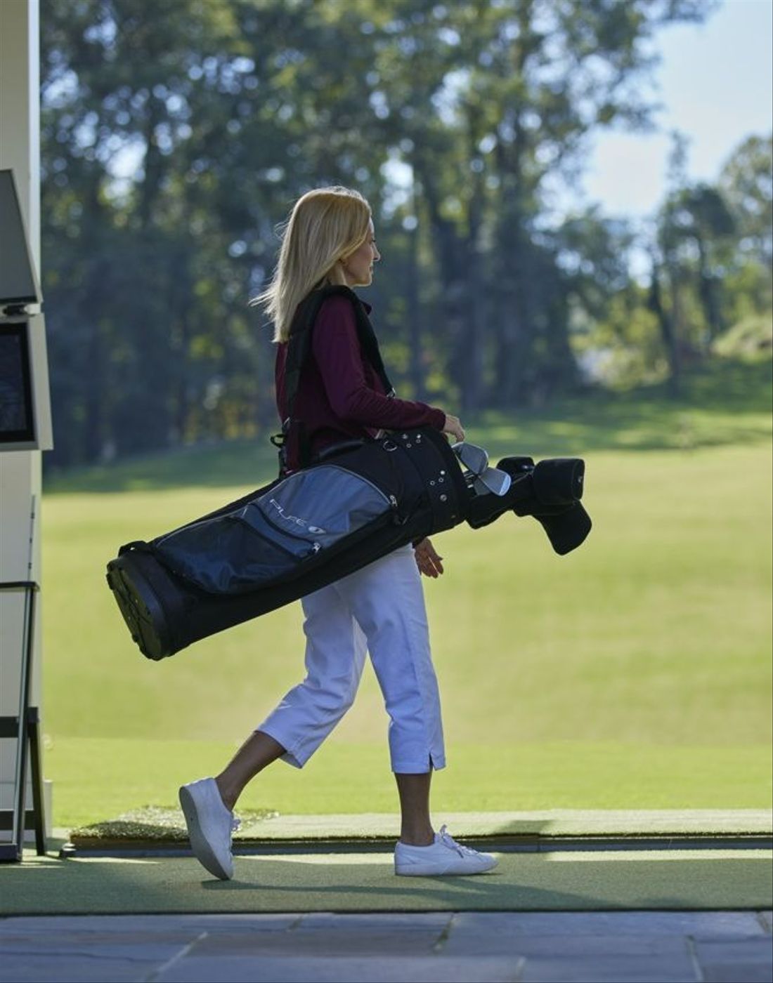 Woman walking over to use Toptracer driving range on a sunny day