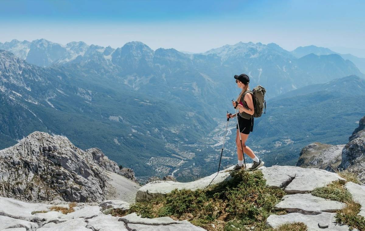 Young fit woman hiking in Albanian Alps mountains during summer travel adventure. Female walking alone on rocky path with to…