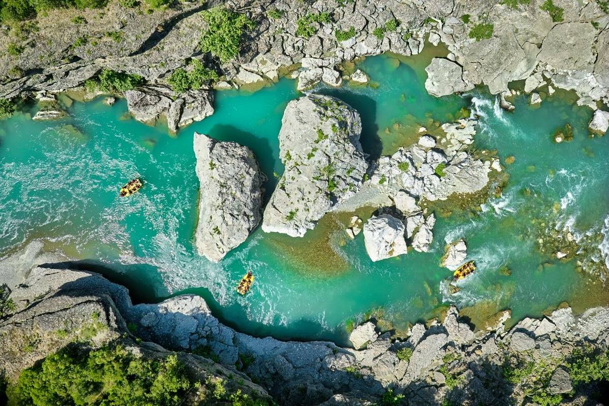 White water rafting.  Adventure and sport. A yellow raft floating among the rocks on the crystal clear, blue-green water. Pe…
