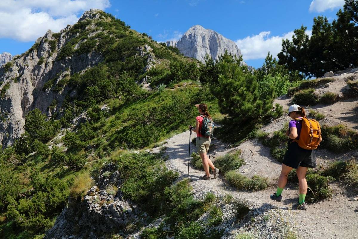 Women tourists hiking in sunny weather in Theth Mountains in Albanian Alps (also known as Accursed Mountains). Alps of Alban…