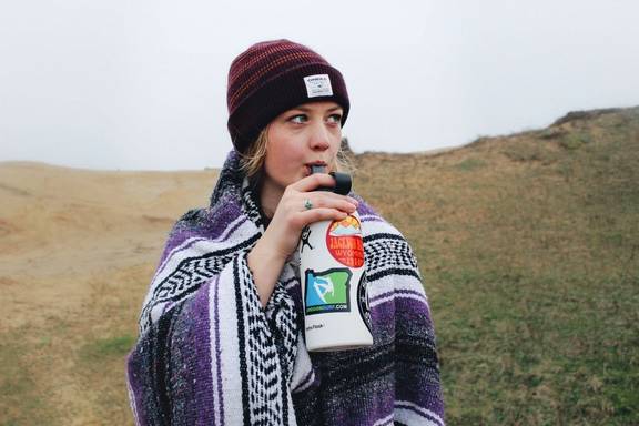 Woman using a reusable bottle to drink water whilst travelling