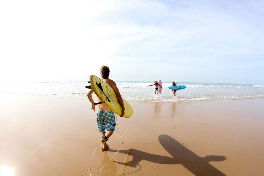 Group of surfers going into the sea with their surfboards