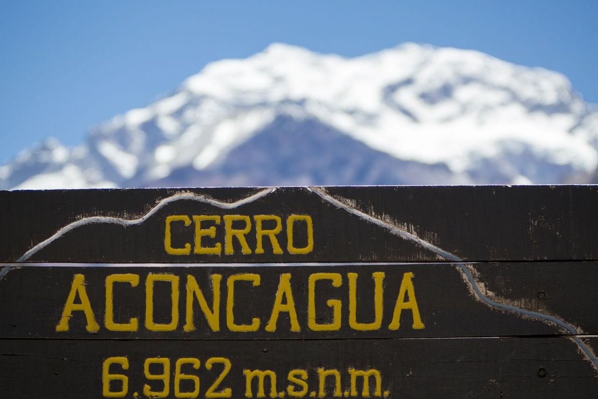 Welcome wooden sign at the Aconcagua National Park with the peak of the mountain at 6962 meters above sea level and a clear …