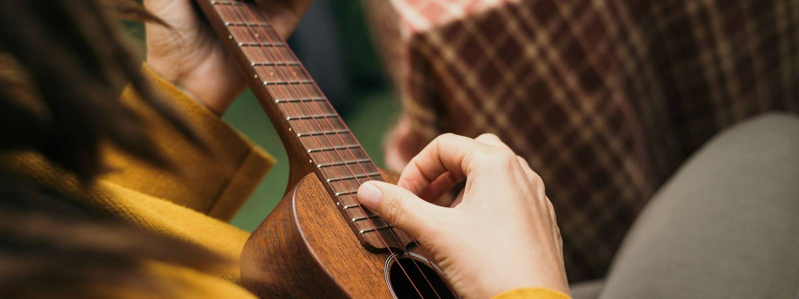 girl with dreadlocks closeup playing an acoustic instrument ukulele in autumn on the terrace.