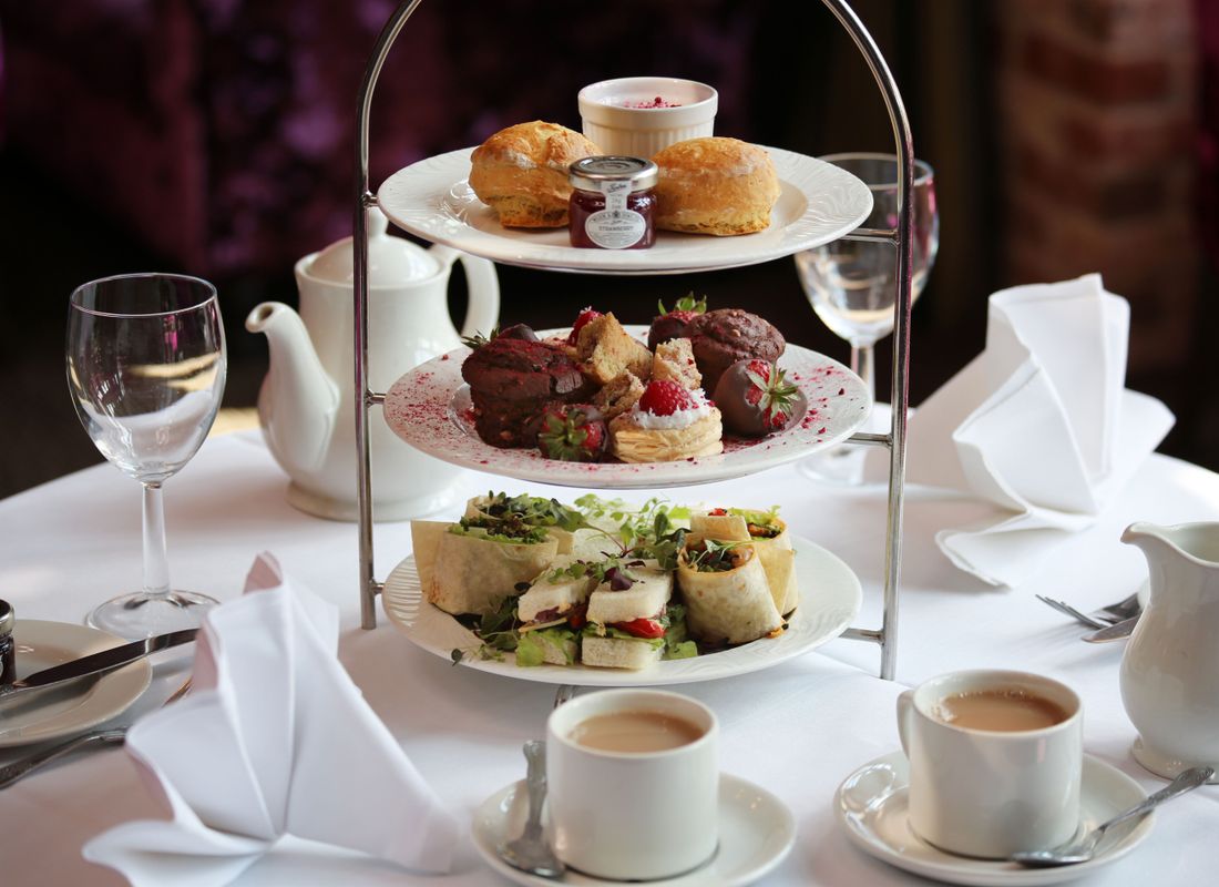 Three tiers of afternoon tea set with two cups of tea for friends and family