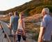 Group Of Senior Friends Walking Along Boardwalk At Beach On Summer Group Vacation