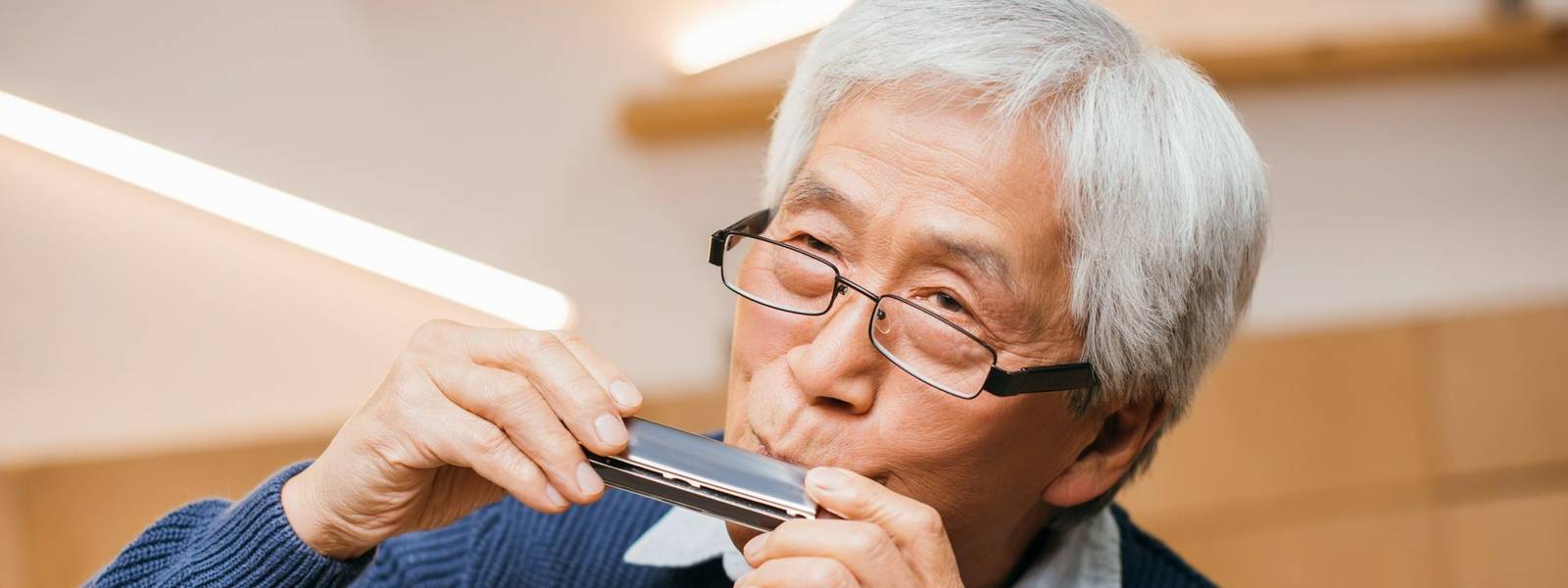 portrait of happy senior asian man playing harmonica