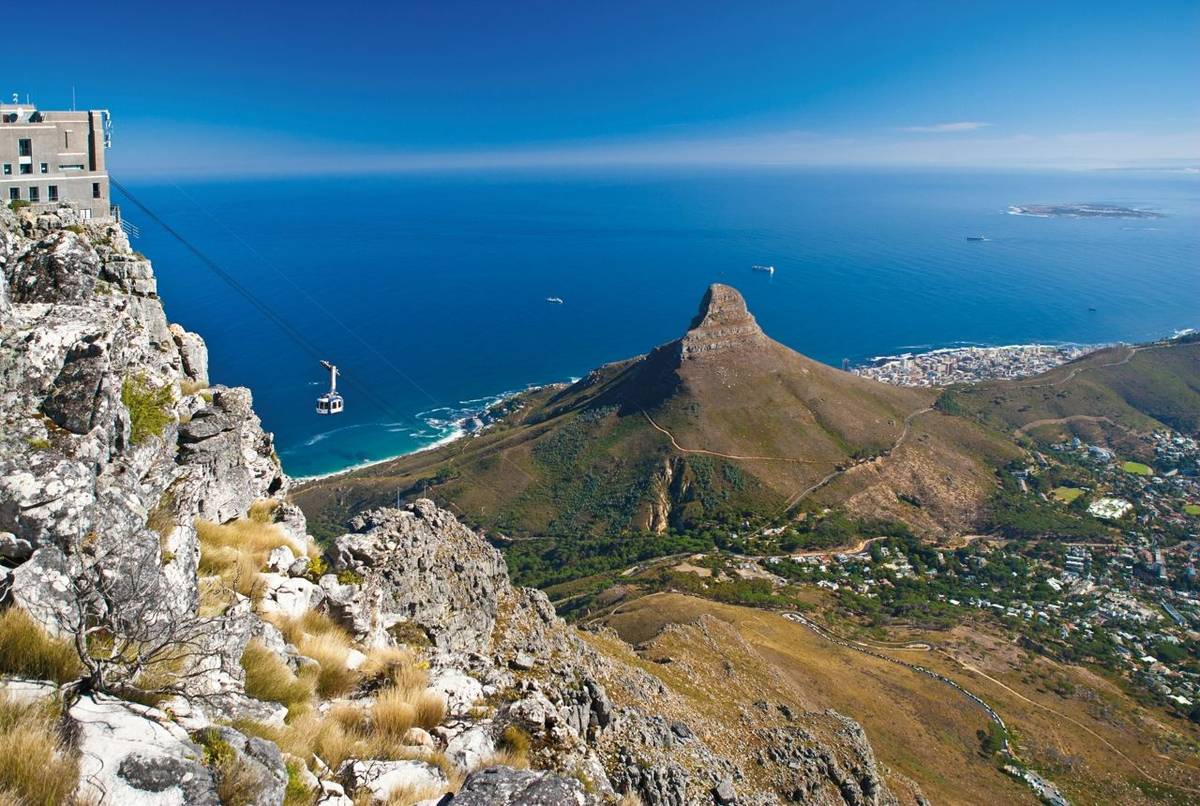Table Mountain cable car ascending to top station with Robben Island in the background