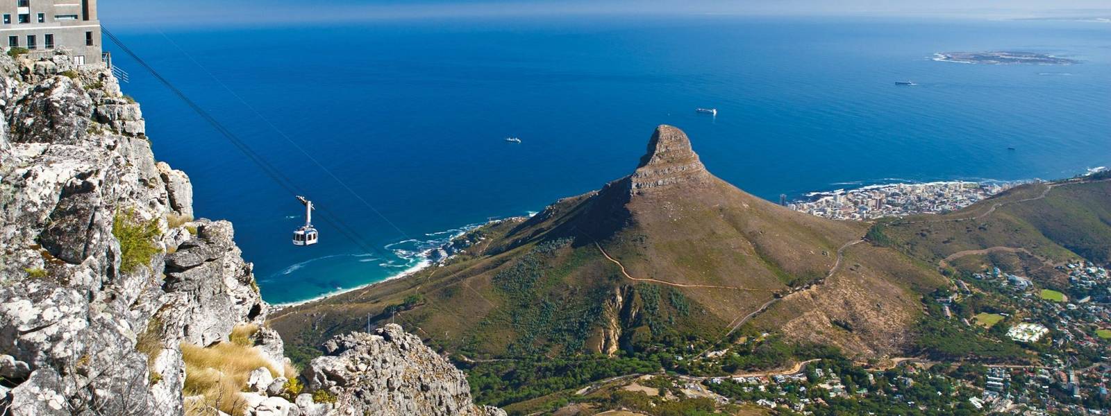 Table Mountain cable car ascending to top station with Robben Island in the background