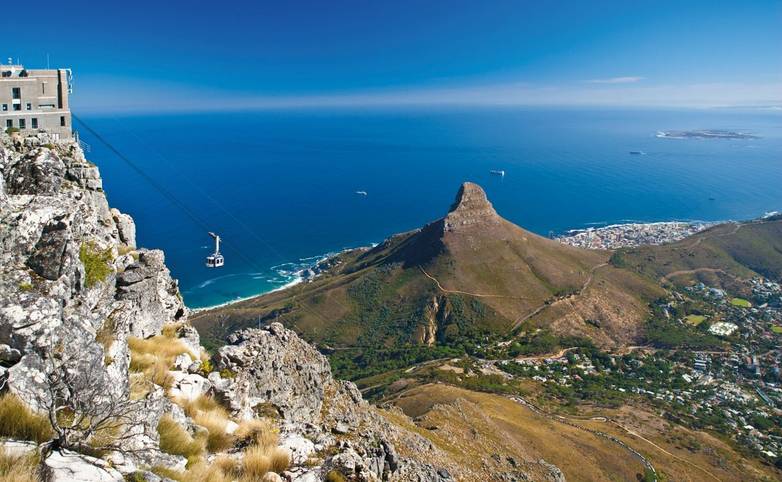 Table Mountain cable car ascending to top station with Robben Island in the background