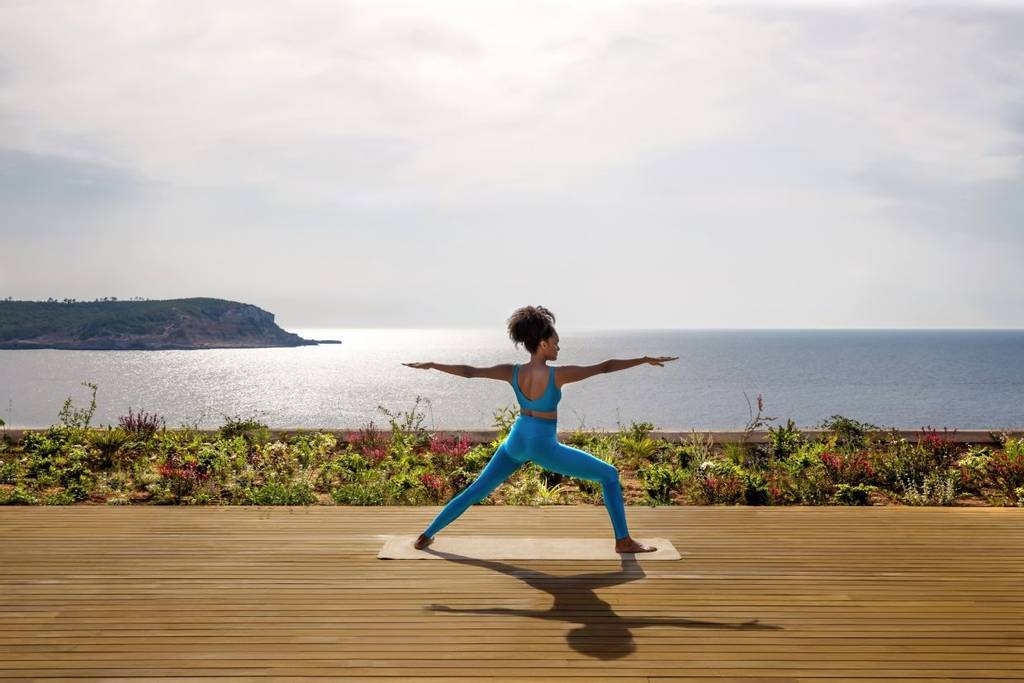 Woman doing yoga by the seaside at Six Senses Ibiza