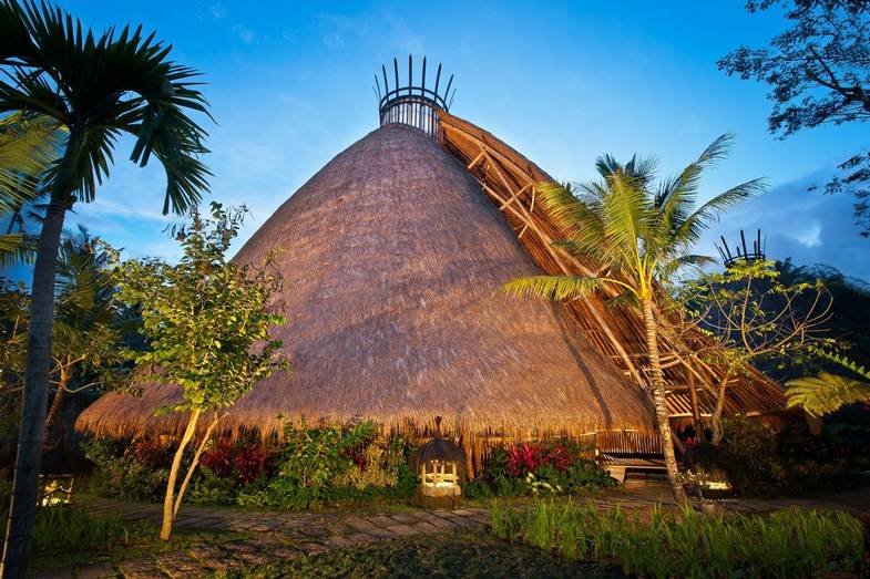 The 10-meter diameter Mandala Agung structure offers a gathering space for large groups. A thick shag of alang alang thatch …
