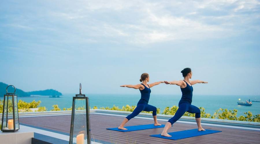 Two people practicing yoga by the sea