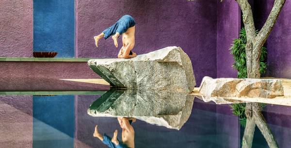 Man doing a headstand on a rock at The Barai Spa in Thailand