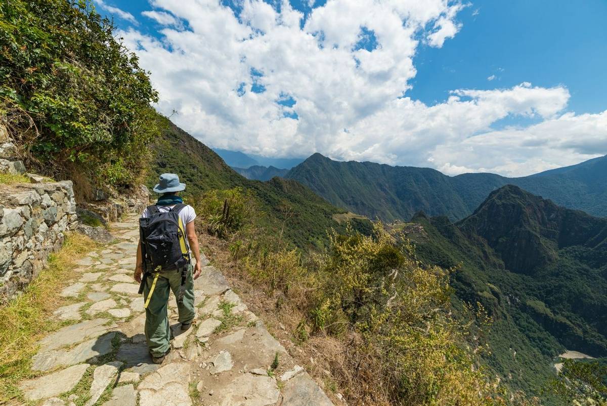 Backpacker exploring the steep Inca's footpaths of Machu Picchu, the most visited travel destination in Peru. Summer adventu…