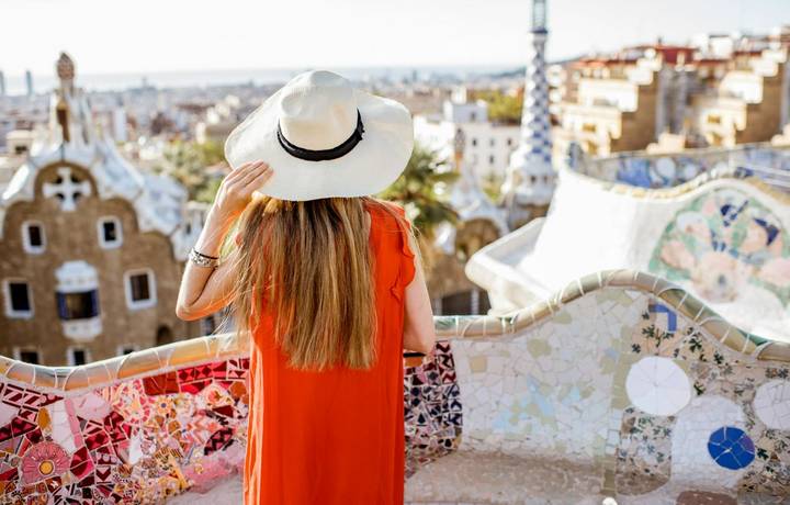 Young woman tourist in red dress enjoying great view on Barcelona city in famous Guell park Young woman tourist in red dress enjoying great view on Barcelona city in famous Guell park