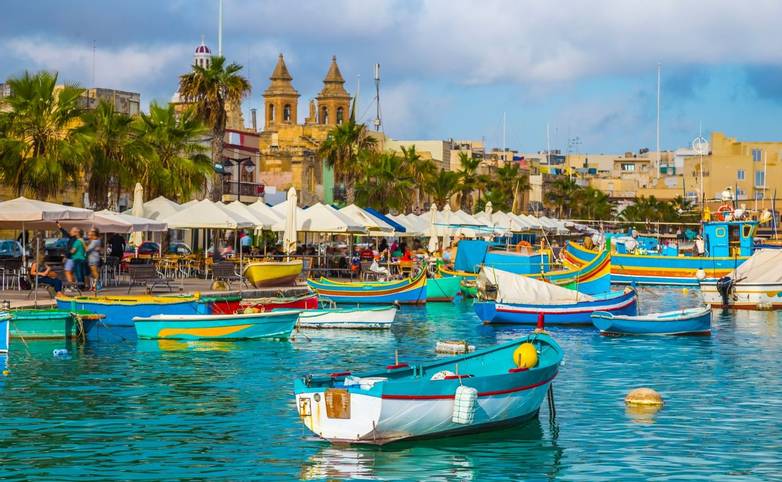 Marsaxlokk, Malta - Traditional colorful maltese Luzzu fisherboat at the old village of Marsaxlokk with turquoise sea water …