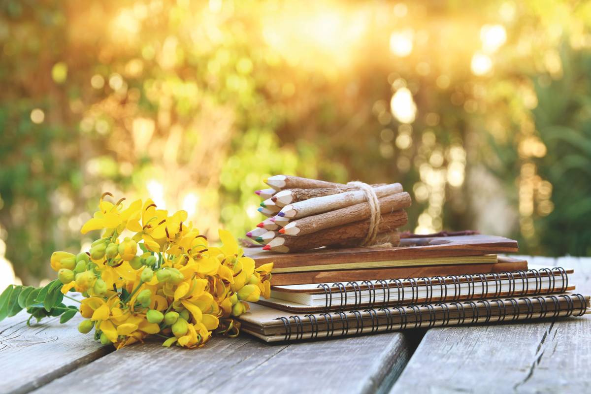 Image of notebooks, colorful pencils on wooden table outdoors at afternoon. selective focus