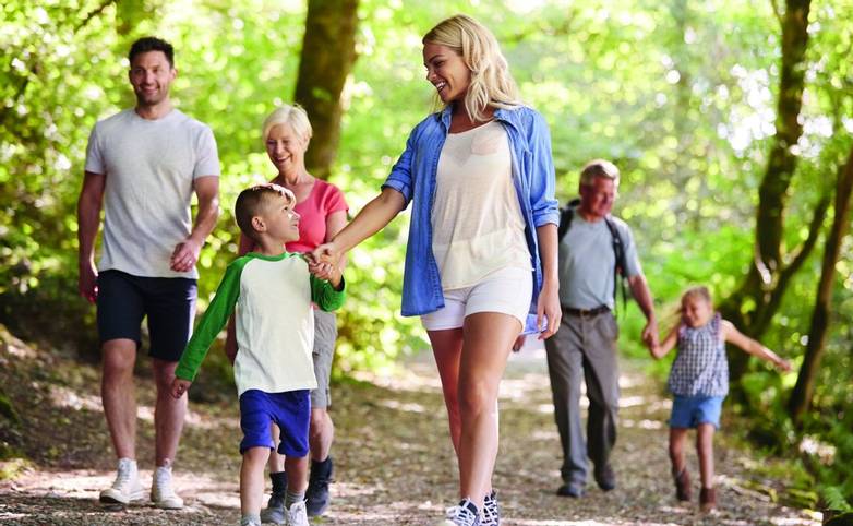 Multi Generation Family Enjoying Walk Along Woodland Path Together