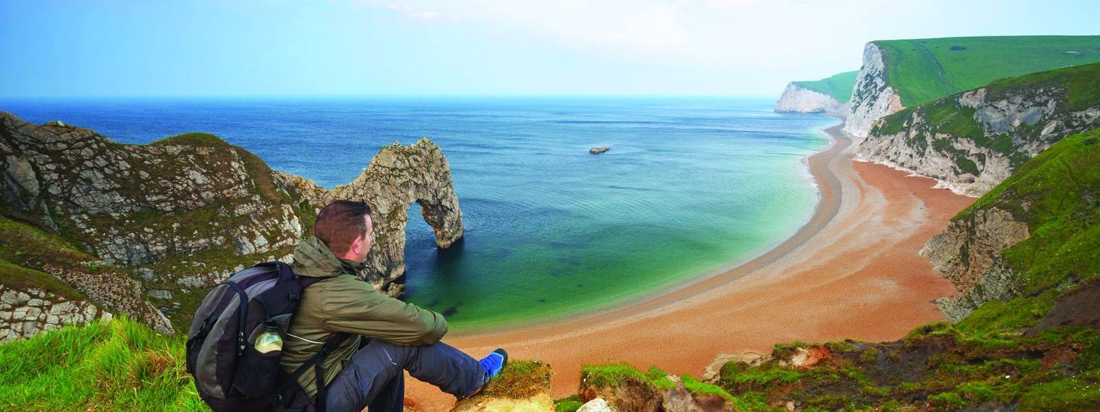 Man watching sunrise over Jurassic coast of Dorset, UK
