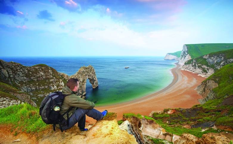 Man watching sunrise over Jurassic coast of Dorset, UK