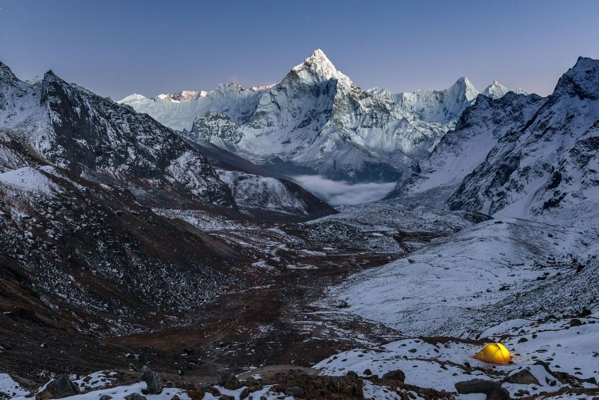 Night camping near amazing Ama Dablam peak in snowy Himalayan mountains, Nepal. Extreme mountain camping concept, yellow ten…