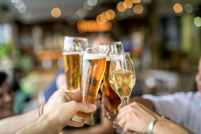 Cropped image of people toasting drinking glasses. Friends are celebrating and enjoying at bar. They are spending leisure ti…