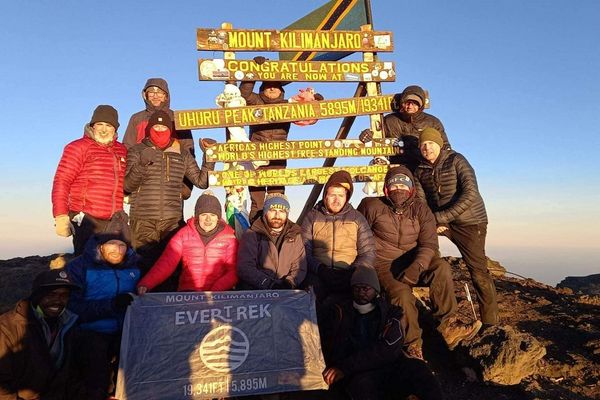 Hikers at the summit of Kilimanjaro, Uhuru Peak, holding up an EverTrek banner