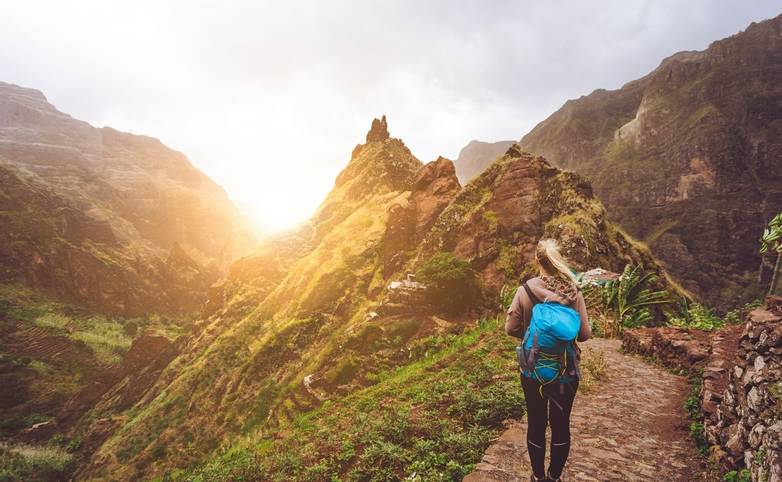 Girl walking down along the trekking route to verdant Xo-Xo valley. Warm sunlight seable on horizont. Santo Antao Island Cap…