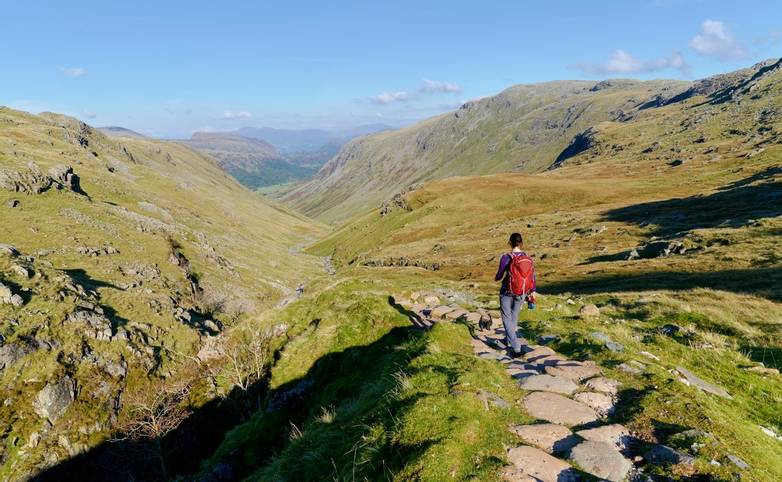 A hiker walking down towards Seathwaite, Grains Gill from Scafell Pike in the English Lake District. UK.