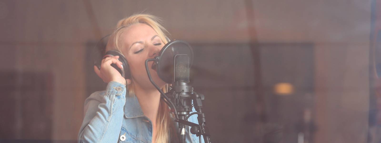 Young woman recording a song in a professional studio
