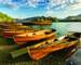 Wooden Rowing Boats lined up on shoreline being illuminated with golden light from the setting sun. Derwentwater, Lake Distr…
