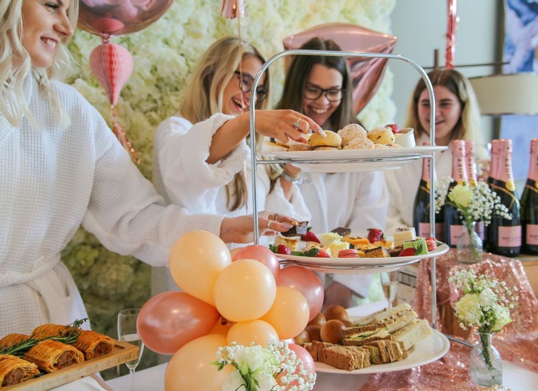 Friends sharing a large afternoon tea and Prosecco during their Hen Do party