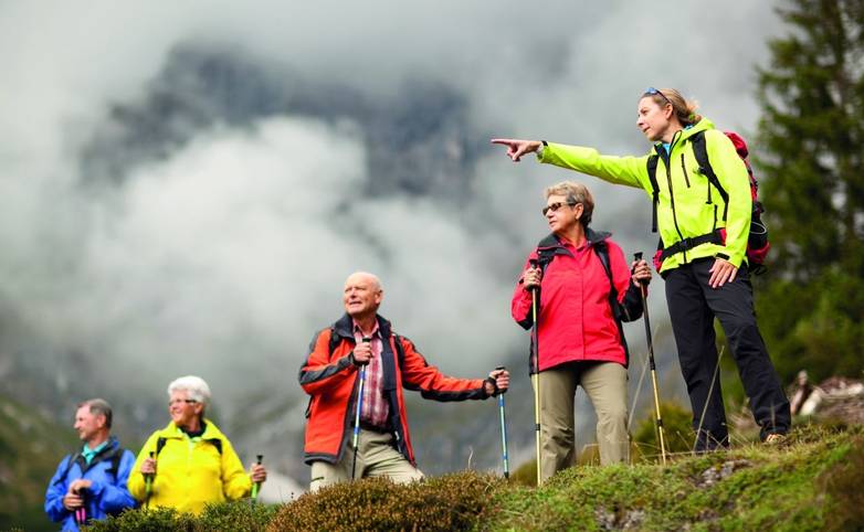 A leader pointing out a landmark to a group of seniors on a guided walking holiday