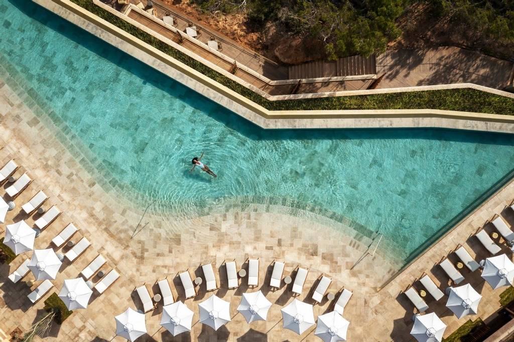 Woman floating in the pool on her summer holiday at Six Senses Ibiza