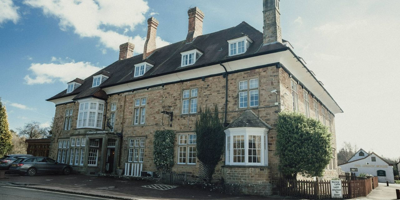 Three storey hotel with sand-coloured brick and white windows.
