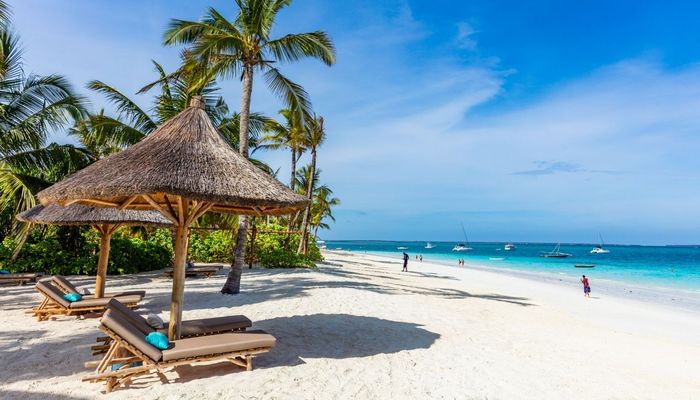 A pristine beach in Zanzibar, with beach beds and a clear blue sea