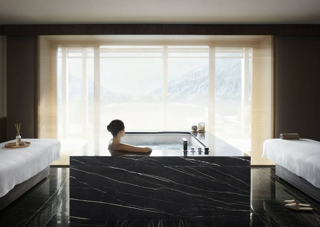 woman in bath tub at Lefay Resort and Spa Dolomiti looking out at the mountains